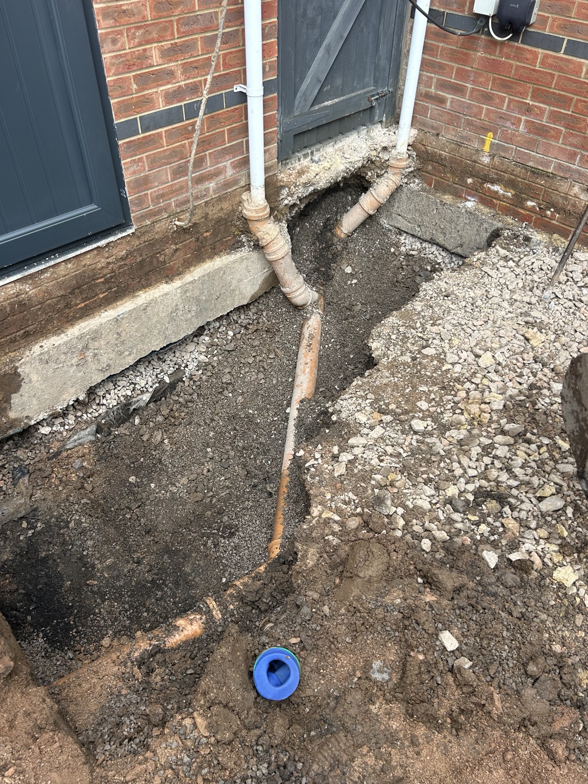 Existing underground drainage pipework exposed beside a property